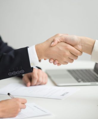 Koncepcja uścisku dłoni w miejscu pracy, kobieta z działu HR i odnosząca sukcesy kandydatka ściskają sobie dłonie, przygotowując się do podpisania umowy o pracę, pracodawca gratuluje nowemu pracownikowi, widok z bliska