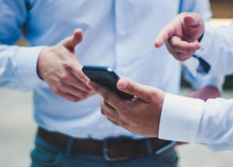 dwóch mężczyzn patrzących i analizujących dane z telefonu